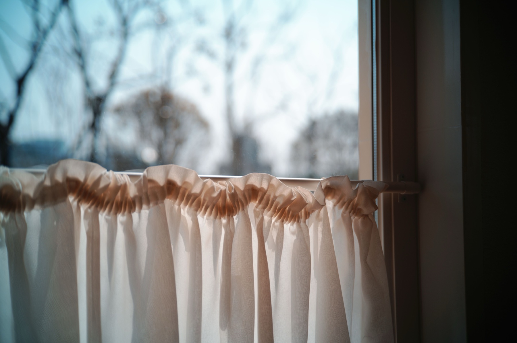 Warm sunlight through gathered curtain fullness on a rod